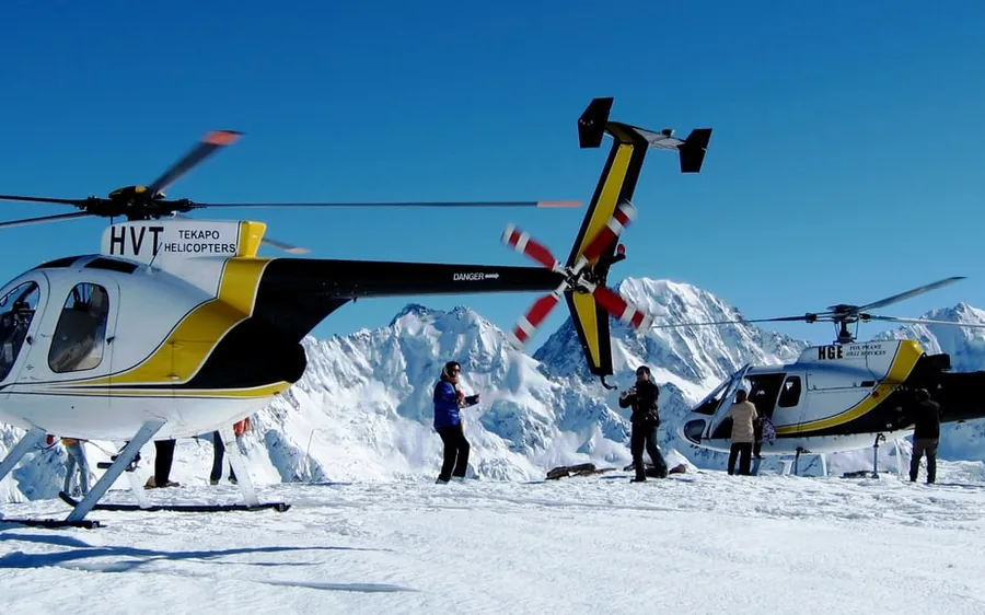 A helicopter on a snow landing site with passengers taking photographs