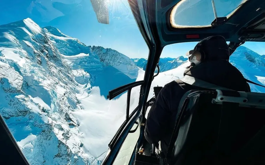 A helicopter above the blue ice of the Southern Alps